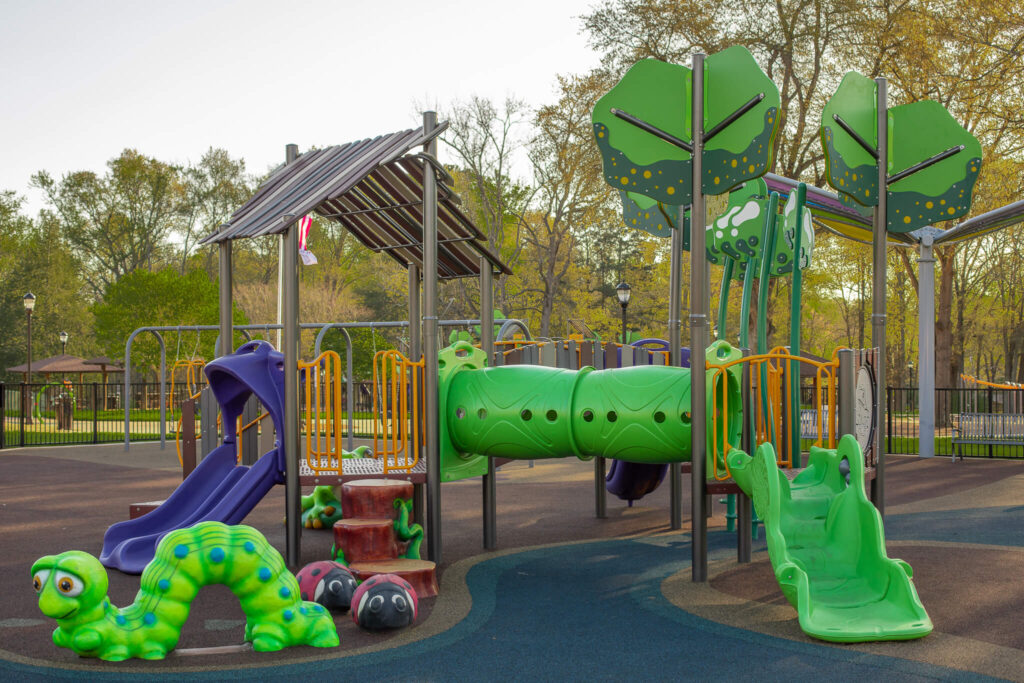 A colorful playground with multiple slides with large plastic ladybugs and a caterpillar.