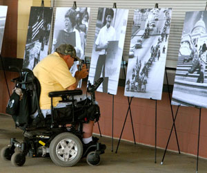 man in wheelchair looking at posters from the disability rights movement