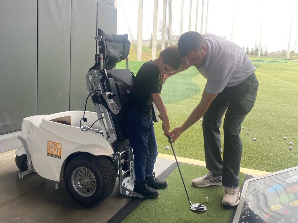 A golf coach teaches a young boy how to hit the golf ball.