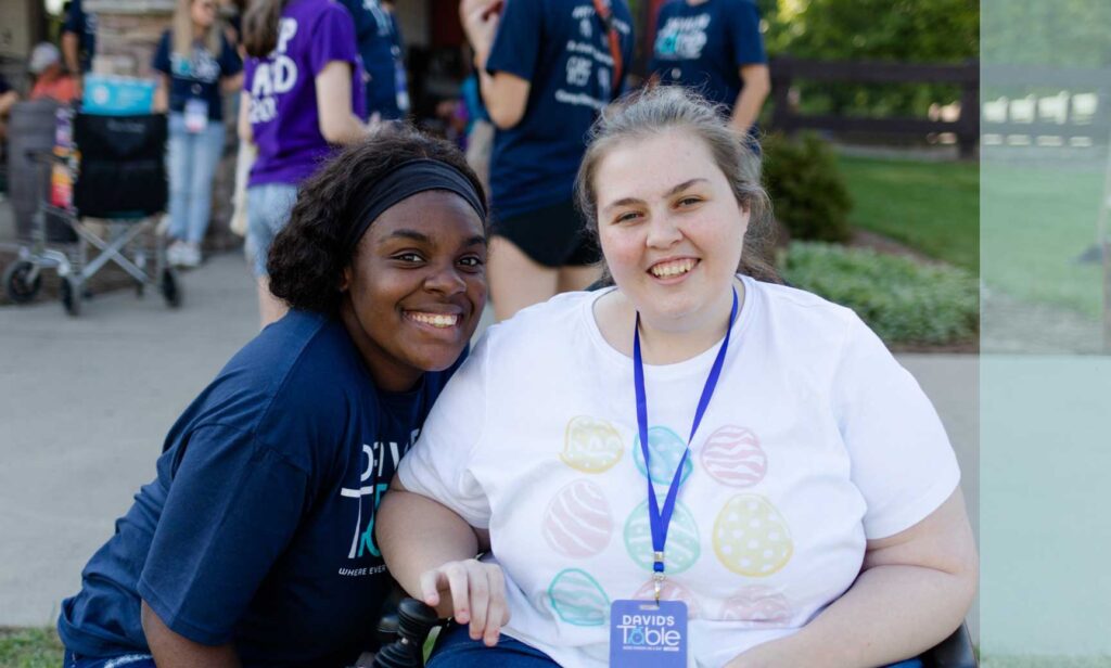 Two young women smile next to each other.