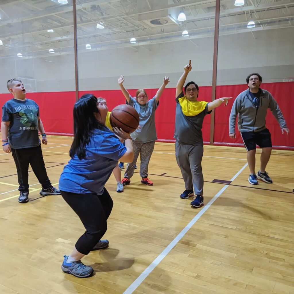 A girl shoots the basketball while her team looks on.