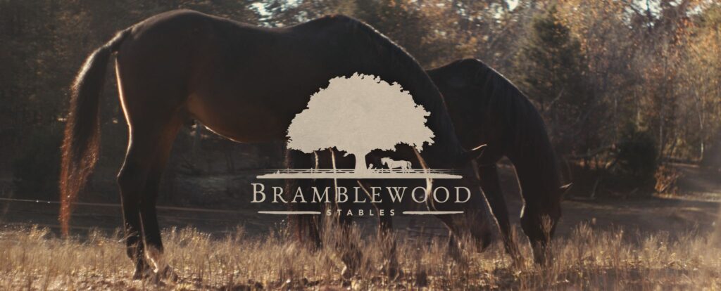 A photo of two horses feeding with the words Bramblewood Stable written across it.