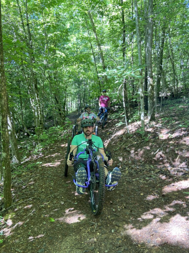 Two adaptive riders face the camera, with a non adaptive rider in the back.