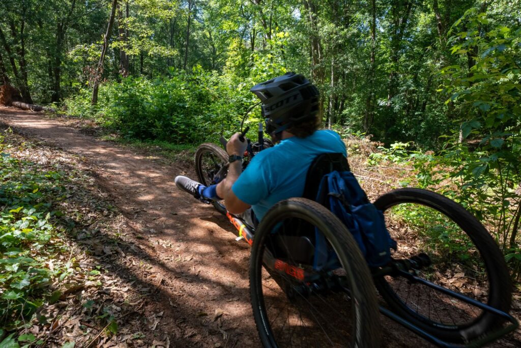 Man in a blue shirt riding on an adaptive handcycle.